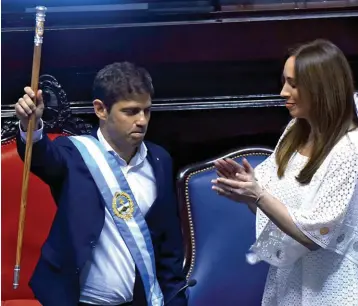  ??  ?? RIVALES. Kicillof recibe el bastón de manos de Vidal, criticada en redes por su look "cortina de baño".