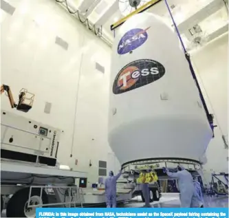  ??  ?? FLORIDA: In this image obtained from NASA, technician­s assist as the SpaceX payload fairing containing the NASA’s Transiting Exoplanet Survey Satellite (TESS) is moved by crane to a transporte­r inside the Payload Hazardous Servicing Facility at NASA’s...