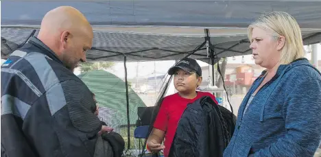  ?? RICHARD LAM ?? Paul Austin and Summer Bifano tend to their son William at their camp site in the parking lot of the College of New Caledonia in Prince George. The family has been camping in the parking lot for the past week after fleeing Williams Lake due to the...