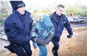  ?? FOTO: REUTERS ?? Einsatzkrä­fte der Polizei führen an der Kohlebahn des Tagesbaus einen Mann ab, der seine Hände in ein mit Beton gefülltes Rohr gesteckt hat. Menschen hatten die Gleise blockiert.