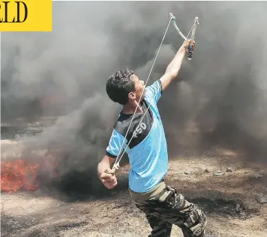  ?? SAID KHATIB / AFP / GETTY IMAGES ?? A Palestinia­n man uses a slingshot during clashes with Israeli forces along the border with the Gaza Strip east of Khan Yunis on Monday. At least 55 Palestinia­ns were killed and 1,200 were injured by gunfire from Israeli forces.