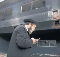  ?? ?? Rabbi Mendel Weinfeld checks his phone outside of the fire-damaged Chabad House.