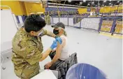  ?? LUIS SÁNCHEZ SATURNO/THE NEW MEXICAN ?? Louis Smith of Santa Fe gets her COVID-19 vaccine Tuesday from Pfc. Marisa Miranda of the New Mexico National Guard at the Department of Health’s vaccinatio­n center in the Santa Fe High School gymnasium.