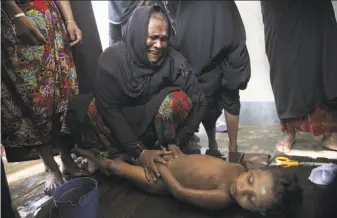  ?? Paula Bronstein / Getty Images ?? A woman weeps while preparing the body of a child for a funeral. More than 60 people died when a boat carrying Muslim refugees from Myanmar sank off the coast of Bangladesh.