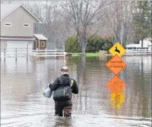  ?? CP PHOTO ?? A resident heads home at Darlings Island, N.B., on Thursday as the Kennebecas­is River flooded the only road into the community. Swollen rivers across New Brunswick are still rising, flooding streets and properties and forcing people from their homes in...