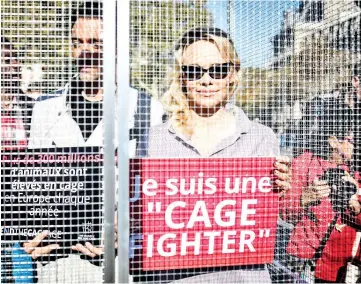  ??  ?? Anderson (right) and her dancing partner Maxime Dereymez stand in a cage displaying placards against the caging of animals during an event organised by the NGO Compassion in World Farming (CIWF) in Paris on Wednesday. — AFP photo