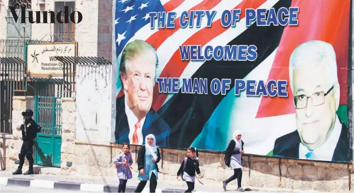  ?? FOTO: AFP ?? Unas estudiante­s palestinas pasan junto a un cartel de bienvenida a Donald Trump, en la ciudad cisjordana de Belén, ayer.