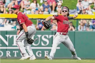  ?? Ross D. Franklin/Associated Press ?? Arizona Diamondbac­ks center fielder Corbin Carroll, right, throws to the infield after making a catch on a pop fly, as he avoids a collision with shortstop Nick Ahmed, left, during a spring training baseball game on Thursday in Mesa, Arizona.