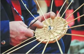  ?? WANG BIAO / FOR CHINA DAILY ?? A craftsman makes a piece of wickerwork at a handicraft fair held in Funan county, Anhui province. More craftsmen are using straw as the raw material for their creations.