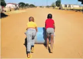  ?? ?? EVEN CHILDREN SPEND THE BETTER PART OF THEIR DAYS ROLLING THE HEAVY WATER DRUMS ALONG THE WIDE, SANDY STREETS OF MARULANENG.