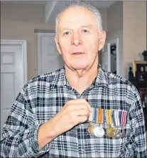  ?? SAM MCNEISH/THE TELEGRAM ?? Everett Green, the son of Able Seaman Leander Green, poses with the medals his father won, including his distinguis­hed bravery medal for an act of heroism on Jan. 1, 1915, when he jumped into the frigid ocean and swam to a sinking vessel with a rope in tow.