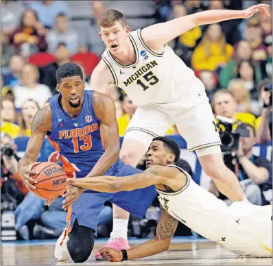  ?? [NATI HARNIK/THE ASSOCIATED PRESS] ?? Michigan’s Charles Matthews, bottom, Jon Teske (15) and Florida’s Kevarrius Hayes scramble for the ball during the first half.