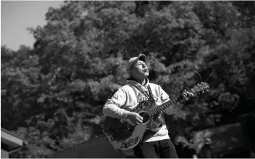  ?? — AFP photos by Behrouz Mehri ?? In this picture taken on Nov 1, Japanese musician Kyochi Watanabe plays his guitar as he poses for a photo at the entrance of Aokigahara Forest, known as Suicide Forest, in Narusawa village, Yamanashi prefecture.