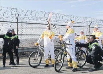  ?? AP ?? A torchbeare­r passes the flame near a wire fence after crossing the Unificatio­n Bridge during the Olympic Torch Relay for the 2018 Winter Olympics in Paju, South Korea on Friday.