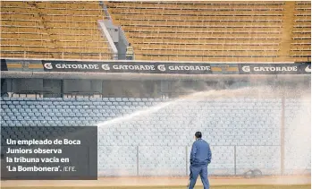  ?? /EFE. ?? Un empleado de Boca Juniors observa la tribuna vacía en
‘La Bombonera’.