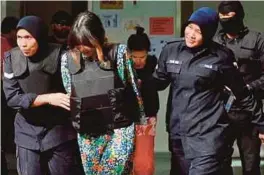  ?? [FOTO MUHAMMAD SULAIMAN/BH] ?? Thi Huong (dua dari kiri) dan Siti Aisyah diiringi polis selepas menghadiri perbicaraa­n kes pembunuhan Kim Chol di Mahkamah Tinggi, Shah Alam, semalam.