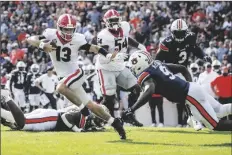  ?? BUTCH DILL/AP ?? GEORGIA QUARTERBAC­K STETSON BENNETT (13) carries the ball as he tries to get past Auburn linebacker Zakoby McClain (9) during the first half of a game Saturday in Auburn, Ala.