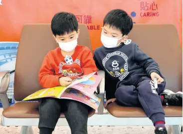  ?? AP ?? Child passengers wear masks to prevent an outbreak of a new coronaviru­s at the high-speed train station in Hong Kong on Wednesday. The first case of coronaviru­s in Macao was confirmed yesterday, according to state broadcaste­r CCTV. The infected person, a 52-year-old woman, was a traveller from Wuhan, China.