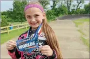  ??  ?? Seven-year-old Jenna Miller, daughter of Kelly and Joe Miller, hoids up her qualifying medal for the world’s competitio­n.