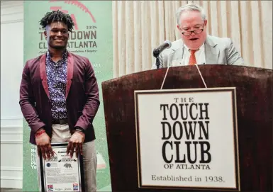  ?? / Rome City Schools ?? Rome High running back Jamious Griffin (left) holds his award for being named the Touchdown Club of Atlanta’s Back of the Week as TCA Board of Governors member Paul Weathingto­n talks about his acievement­s during Monday’s luncheon in Buckhead.