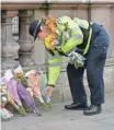 ?? JUSTIN TALLIS, AFP/GETTY IMAGES ?? A police officer lays flowers around a photograph of fellow officer Keith Palmer, who was killed Wednesday.