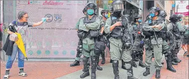  ?? AP ?? ■
Riot police stand guard as a woman tries to cross the street in the Central district of Hong Kong.