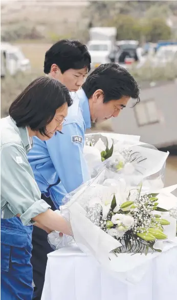  ?? Picture: AP ?? Japanese PM Shinzo Abe, centre, offers flowers for the victims in Kurashiki, Japan.