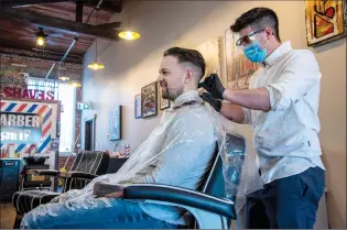  ?? NEWS PHOTO RYAN MCCRACKEN ?? Isaac Maltin cuts Jay Johnson’s hair while wearing a protective mask, glasses and gloves on Thursday at Isaac’s Barber Shop in downtown Medicine Hat. Barbershop­s and hair salons across the city began reopening Thursday under Stage 1 of the provincial government’s relaunch strategy.