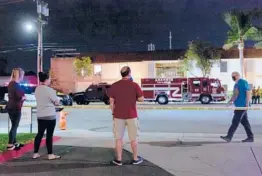  ?? ALLISON ZAUCHA/THE NEW YORK TIMES ?? Onlookers gather at the scene of a mass shooting Wednesday in Orange, California. Four people, including a 9-year-old boy, were killed.