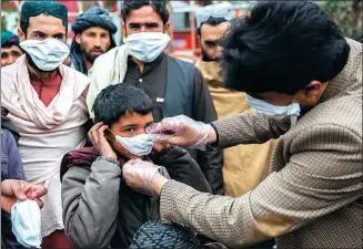  ?? XINHUA ?? A health worker distribute­s masks to locals as a preventive measure following the arrival of the coronaviru­s in Afghanista­n on Wednesday.