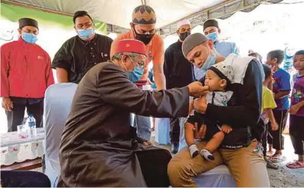  ?? (Foto BERNAMA) ?? Zulkifli menyempurn­akan majlis tahnik, Muhammad Umar Wafi bersama bapanya, Muhammad Asyraf ketika menghadiri Program Kembara Kasih Mualaf di Kuala Boh, semalam.