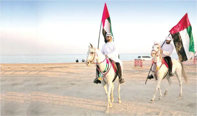  ?? ?? Emirati men on horseback proudly ↑ display the national flag.