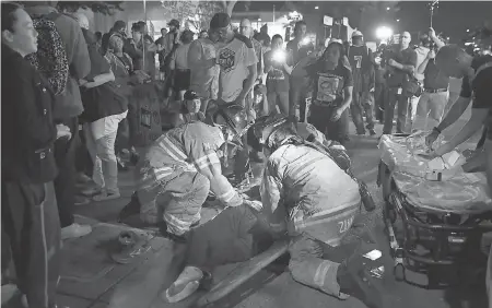  ??  ?? Emergency responders provide medical care Saturday night to a woman who was struck by a Sacramento County Sheriff’s Department vehicle, which left the scene, following a rally and vigil for Stephon Clark. ELIJAH NOUVELAGE/EPA-EFE