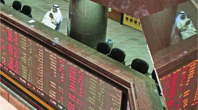  ??  ?? KUWAIT: A trader follows the stock market at the Kuwait Stock Exchange (KSE) in Kuwait City. Kuwait stocks ended yesterday’s trading on a mixed board. The benchmark dropped by 2.07 points to settle 6,801 points, while Weighted and KSX 15 indices went...