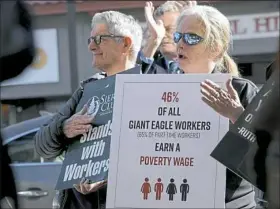  ?? Pam Panchak/Post-Gazette ?? Tom Hoffman of Point Breeze and Marie Conley of New Kensington clap Wednesday during comments on the Keystone Research Center report at a rally across the street from the Squirrel Hill Giant Eagle on Murray Avenue.