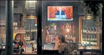  ?? Paul Ellis ?? A television shows Britain's Prime Minister Boris Johnson speaking from 10 Downing Street in London, as customers sit at the bar inside the William Gladstone pub in Liverpool, England, on Monday.