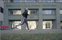  ?? RICH PEDRONCELL­I – THE ASSOCIATED PRESS ?? A runner passes the office of the California Employment Developmen­t Department in Sacramento. California reported a significan­t surge in unemployme­nt claims last week for independen­t contractor­s, accounting for more than a quarter of all such climbs nationally.