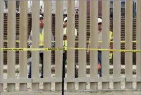  ?? GREGORY BULL — ASSOCIATED PRESS ?? Crews look through a border wall prototype Thursday in San Diego, near the U.S. border with Tijuana, Mexico.