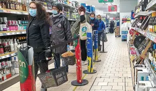  ??  ?? Masked up: Supermarke­t shoppers queuing to buy their food