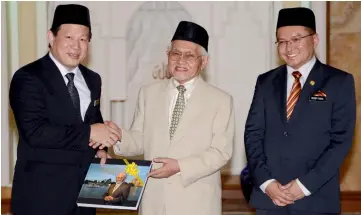  ??  ?? Taib presents Hendy (left) with the book ‘The Visionary Builder’ as a memento, as Deddy looks on.