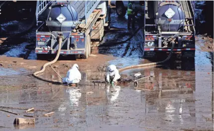  ??  ?? Workers in hazmat suits pump out muddy water from U.S. Highway 101 at Montecito. TREVOR HUGHES/USA TODAY