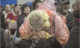  ?? AP PHOTOS ?? HUNKERING DOWN: A man, above, rests while waiting to board a bus headed for San Antonio at an evacuation center yesterday in Corpus Christi, Texas. Below right, a tractor-trailer tilts under the onslaught of high winds and rain.