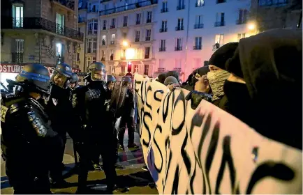  ?? PHOTO: REUTERS ?? French riot police face off with people holding a banner with the message that reads, ‘‘Cops Rapists Murderers’’ to protest police brutality after a young black man was severely injured during his arrest earlier this month in Paris.