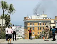  ?? AP/ERIC RISBERG ?? People stop to watch black smoke billow from the Russian Consulate in San Francisco on Friday. Fire officials determined the smoke was coming from a chimney as some things were being burned.