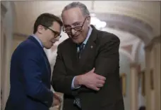  ??  ?? Senate Minority Leader Chuck Schumer, D-N.Y., confers with his communicat­ions aide Matt House as he speaks to reporters following a closed-door strategy session on Capitol Hill in Washington on Tuesday. AP PHOTO/J. SCOTT APPLEWHITE