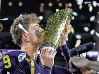  ?? JUNFU HAN/DETROIT FREE PRESS ?? Michigan quarterbac­k J.J. McCarthy kisses the championsh­ip trophy to celebrate the Wolverines’ 34-13 win over Washington in the national championsh­ip game at NRG Stadium in Houston on Monday.