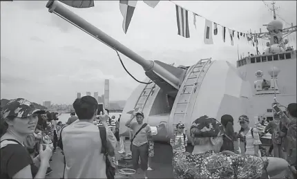  ?? HONG KONG
-AP ?? Visitors pose for photograph­s in front of a weapon on the deck of a People's Liberation Army ship during an open day at the Ngong Suen Chau Barracks in Hong Kong.