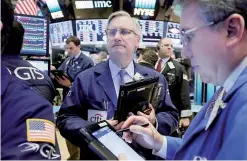  ?? —AP ?? Trader Christophe­r Fuchs, center, works on the floor of the New York Stock Exchange, Tuesday, April 4, 2017. Stocks are edging lower in early trading on Wall Street with banks and energy companies taking the biggest losses.