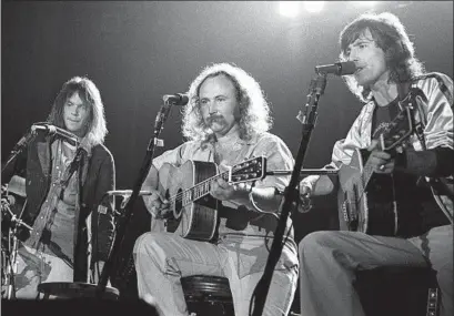  ?? Ed Perlstein Redferns ?? DAVID CROSBY, center, performs with Neil Young, left, and Graham Nash at the Santa Cruz Civic Auditorium in August 1977.