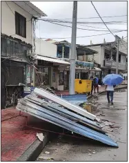  ?? (AP/Daniel Parra) ?? People walk past a damaged buildings in the aftermath of Hurricane Julia Sunday in San Andres island, Colombia.